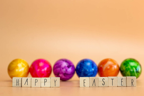 Happy Easter written with pastel colored orange background and colorful fainted Easter eggs, Bright fresh colors, Spring,Easter Holiday, greeting card concept with copy space - Fotografie, Obrázek