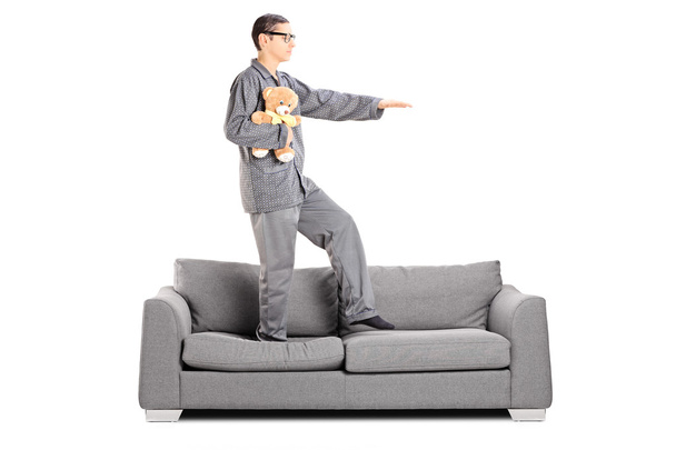 Man in pajamas sleepwalking on sofa - Фото, изображение