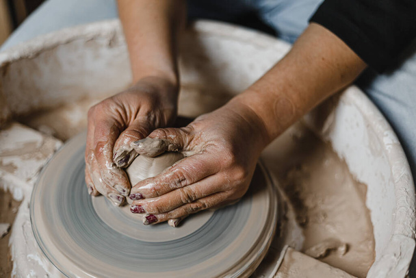 Vrouwelijke handen beeldhouwen mooie borden uit klei tijdens een les in een pottenbakkerij - Foto, afbeelding