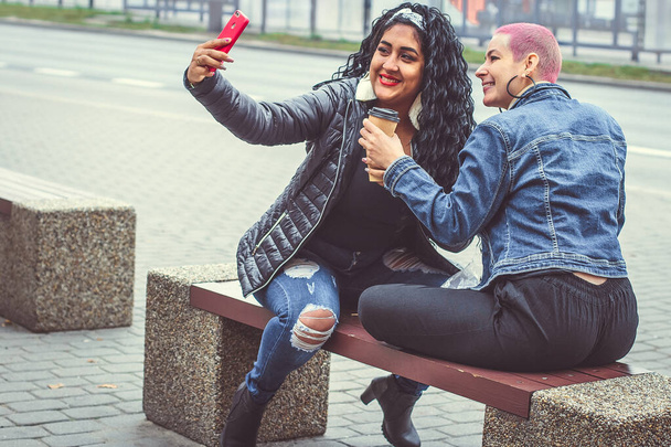 Happy brazilian bright girls take a selfie. Girlfriends have fun outdoors. Friends photographed. Youth lifestyle - Photo, Image