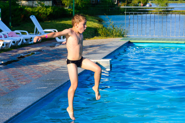 Il ragazzo salta in piscina, giochi per bambini e intrattenimento nel parco acquatico. nuovo - Foto, immagini