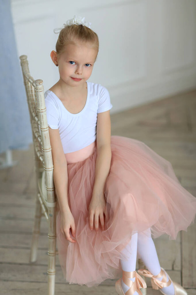 A beautiful ballerina in a pink tutu standing near a ballet stick . Ballet class. Children and ballet - Fotografie, Obrázek