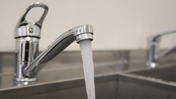 Wasser fließt aus einem verchromten Wasserhahn am Waschbecken - Filmmaterial, Video