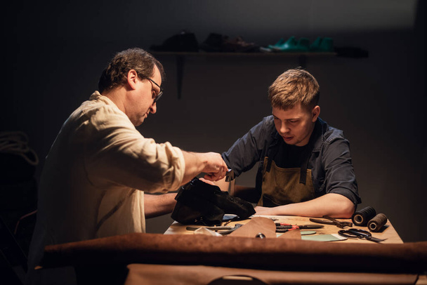 un cordonnier expérimenté et son assistant dans leur atelier fabriquent des chaussures en cuir sur commande. - Photo, image