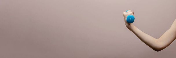 Jungenhand mit Hantel auf rosa Hintergrund. Sportkonzept. Banner, Postkarte und Panorama-Ausgabe. Leerzeichen kopieren - Foto, Bild