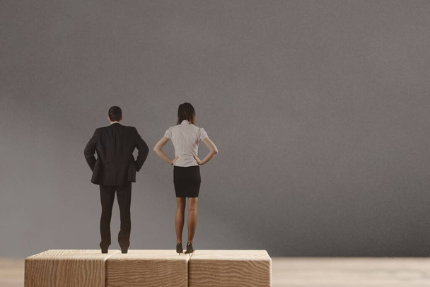 Miniature man and woman standing on the wooden blocks. The concept of the equal opportunities for genders. - Photo, Image