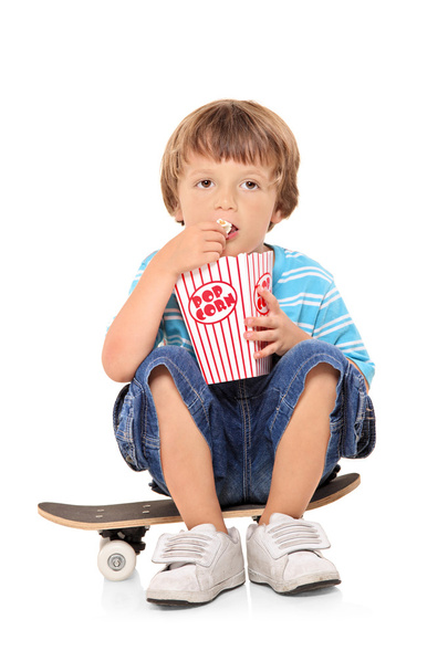 Young boy eating popcorn - Фото, изображение