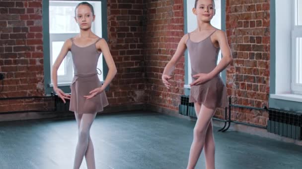 Dwie dziewczyny baleriny trenujące w studiu tańca - stojące w podstawowej pozycji nóg - Materiał filmowy, wideo