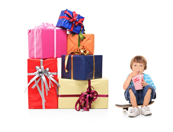 A boy eating a popcorn and pile of gifts - Foto, Imagen