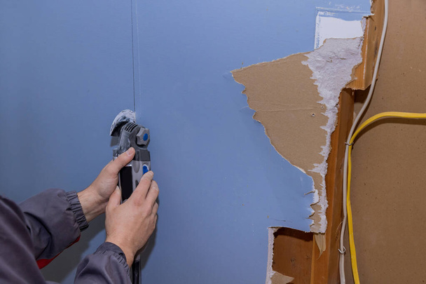 Ремонт будинку по обробці гіпсової гіпсової ручної пилки інструментом з пошкодженим гіпсокартоном
 - Фото, зображення