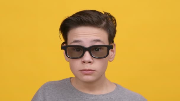Ενθουσιασμένος έφηβος αγόρι φορώντας 3D γυαλιά τρώει ποπ κορν, κίτρινο φόντο - Πλάνα, βίντεο