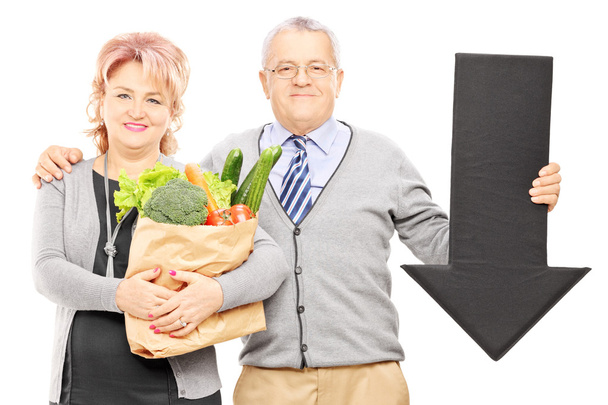 Couple holding groceries and arrow - Foto, imagen