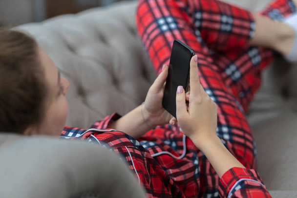 Młoda kobieta robi zakupy online lub social media czatując na kanapie w domu - Zdjęcie, obraz