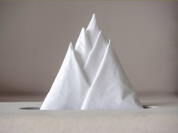 Közelkép kreatív fehér átlátszó szövet papír vagy szalvéta rendezett háromszög hegyi formában a dobozban. - Fotó, kép
