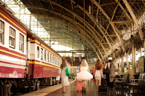 Čtyři ženy tahají kufry pro cestování na vlakovém nádraží, milují výlet a cestu. Concept Tour after post covid, miss you - Fotografie, Obrázek