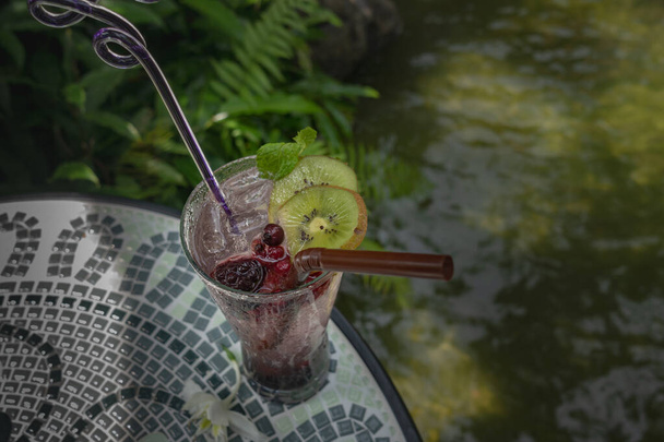 Zumo de uva, kiwi y soda ponen hielo en un vaso transparente - Foto, Imagen