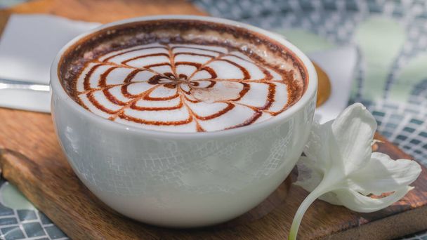 Chique design op hete koffie in witte hete koffiemok, geplaatst op een keramische tafel. - Foto, afbeelding