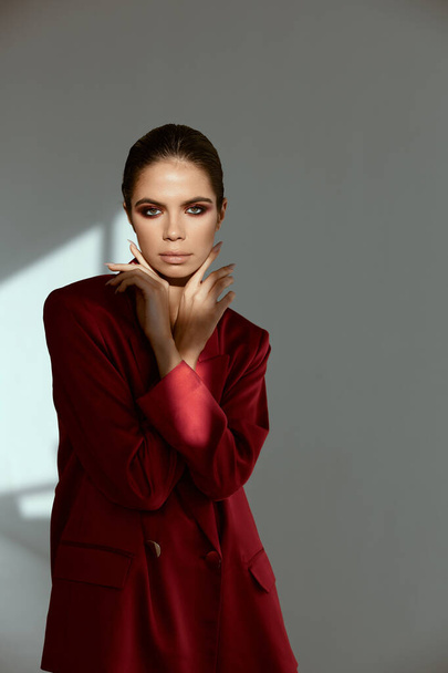 woman holding hands near face charm cosmetics red jacket model - Valokuva, kuva