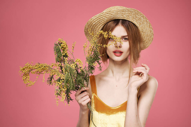 Nainen yllään hattu kimppu mimosa kukkia elämäntapa vaaleanpunainen tausta - Valokuva, kuva