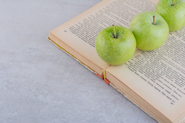green apples and book on grey table background - Photo, Image