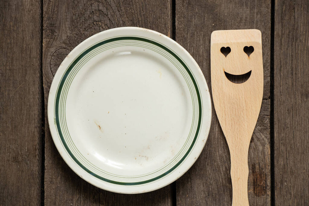 vieille vaisselle blanche en verre vide et spatule en bois avec un sourire sur une table en bois, ustensiles de cuisine - Photo, image