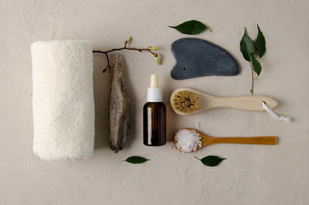Cosmetic product for facials. Concept of natural cosmetics - black stone gouache, cotton towel, brush with natural bristles, serum with natural oil, salt, flat lay - Photo, Image