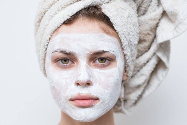 頭にタオルをかけ顔に保湿剤をかけた女性は - 写真・画像