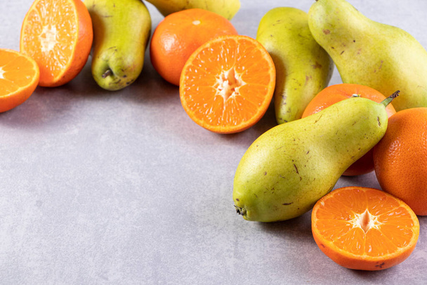 świeże dojrzałe gruszki i mandarynki na szarym tle  - Zdjęcie, obraz
