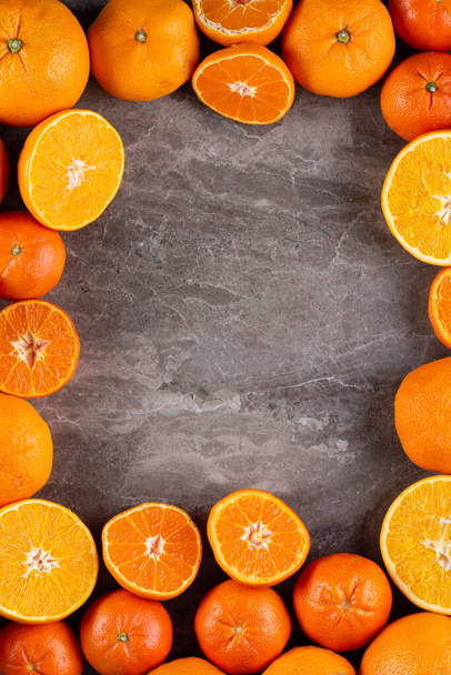 Rahmen aus Orangen und Mandarinen auf grauem Tischhintergrund - Foto, Bild