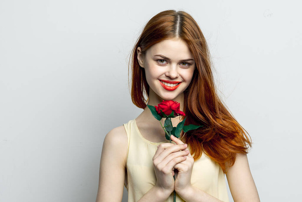 séduisante femme aux cheveux roux lèvres rouges rose fleur dans les mains charme - Photo, image