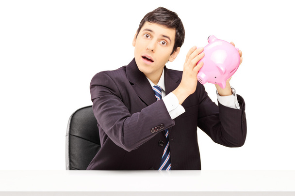 Businessman listening to a piggy bank - Фото, изображение