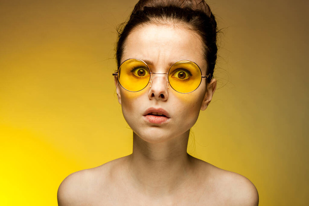 Frau mit nackten Schultern gelbe Brille überrascht Blick aus nächster Nähe - Foto, Bild