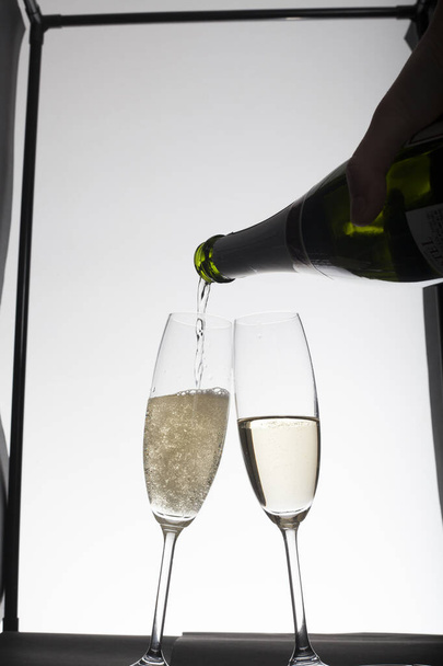 nalévání šampaňského do sklenic na světlém pozadí  - Fotografie, Obrázek