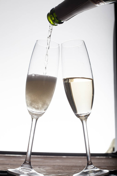 pouring Champagne into glasses against light background  - Foto, Imagen