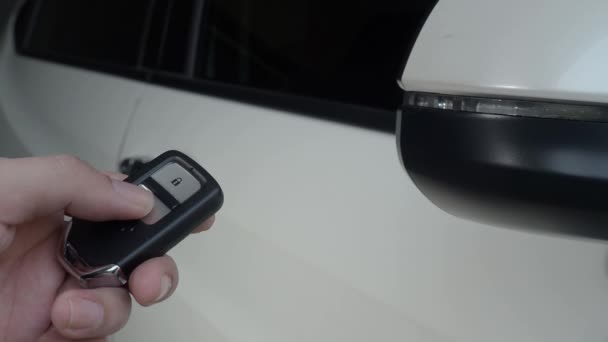 Auton avain kaukosäädin. Auton lukitseminen ja avaaminen auton avaimen kaukosäätimellä. Auton avaimen napin painaminen ja valot vilkkuvat, kun ovi avataan tai suljetaan. Mies käsi etäavaimella. - Materiaali, video