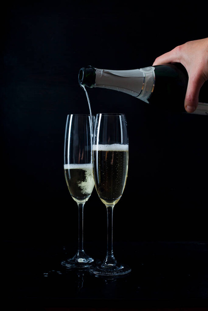 Verter champán en copas sobre fondo negro  - Foto, imagen