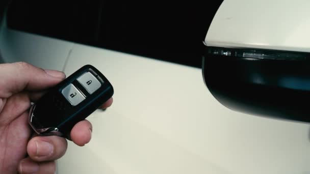 Auton avain kaukosäädin. Auton lukitseminen ja avaaminen auton avaimen kaukosäätimellä. Auton avaimen napin painaminen ja valot vilkkuvat, kun ovi avataan tai suljetaan. Mies käsi etäavaimella. - Materiaali, video
