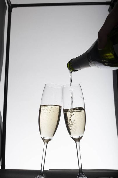 pouring Champagne into glasses against light background  - Foto, Bild