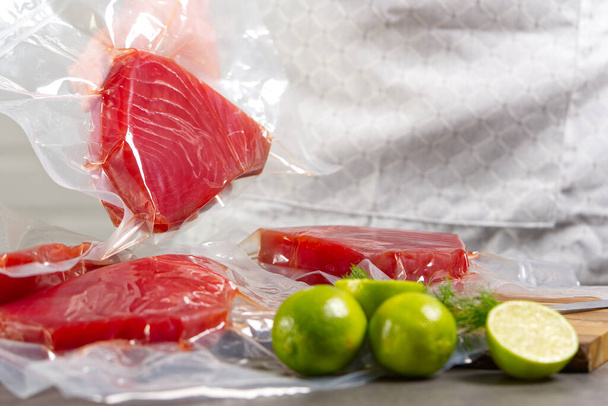 szakács vagy eladó egy halpiacon, aki vákuumzsákba csomagolt kékúszójú tonhal steaket tart - Fotó, kép