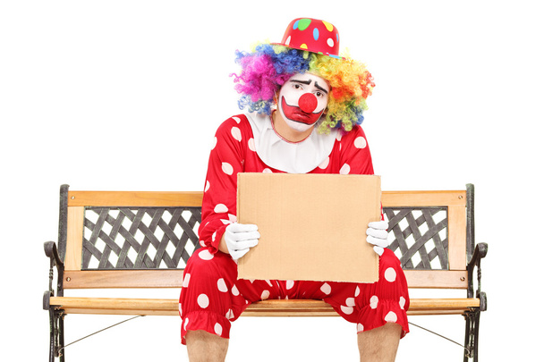 Sad clown holding a blank carton sign  - Фото, зображення