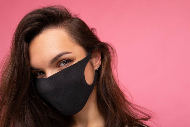 Aufnahme einer jungen attraktiven Frau mit medialer Gesichtsmaske, isoliert über der Hintergrundwand. Schutz gegen COVID-19 - Foto, Bild