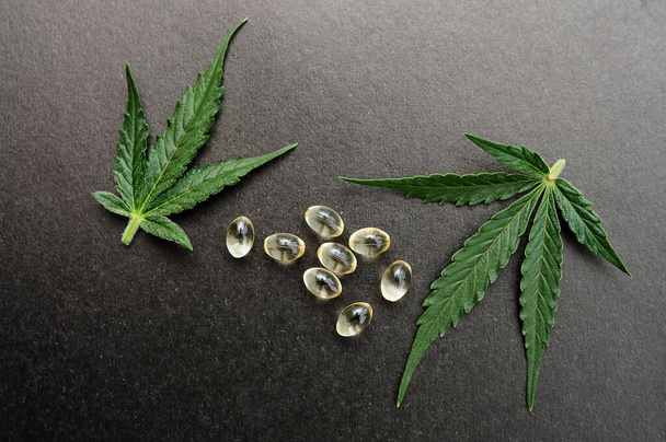 Medizinische Cannabisblätter mit cbd-Öl. Marihuana-Öl in medizinischen Kapseln isoliert auf schwarzem Hintergrund. - Foto, Bild