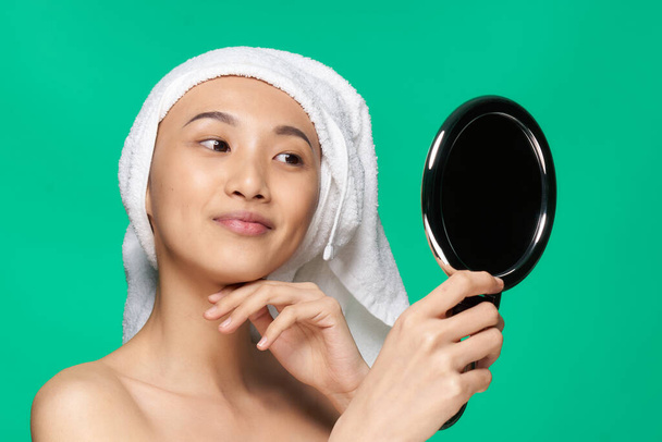 жінка азіатського вигляду дивиться у дзеркало з рушником на її голові чиста шкіра
 - Фото, зображення