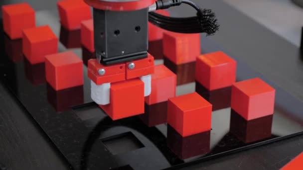 Robot kol manipülatörü robot sergisinde kırmızı oyuncak bloklarını hareket ettiriyor ve yerleştiriyor - Video, Çekim