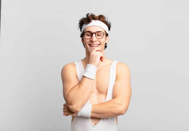 humorous sport man smiling with a happy, confident expression with hand on chin, wondering and looking to the side - Photo, Image