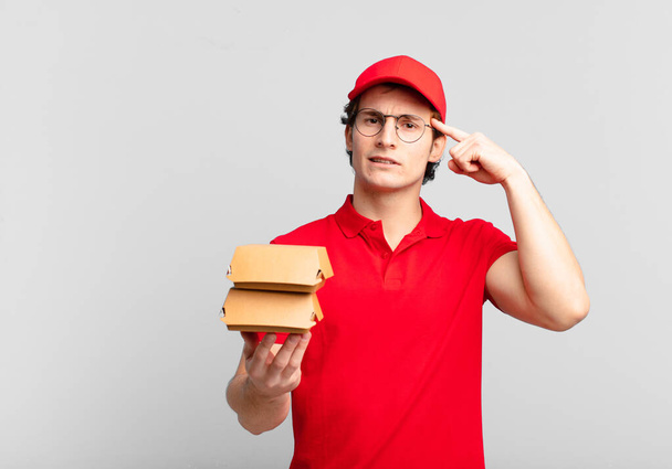 burgers deliver boy feeling confused and puzzled, showing you are insane, crazy or out of your mind - Foto, Bild