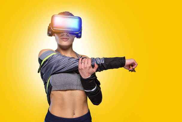 Beautiful sportive caucasian athlete sports woman training - Studio shooting with pretty slim brunette posing during gymnastics workout routine doing stretching wearing hi tech futuristic vr glasses - Photo, Image