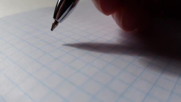 Ręka z niebieskim długopisem pisze "cześć" na papierze w kratkę.. - Materiał filmowy, wideo