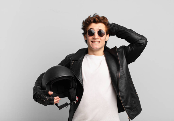 Мальчик-мотоциклист чувствует стресс, беспокойство, тревогу или страх, с руками на голове, паникуя по ошибке - Фото, изображение