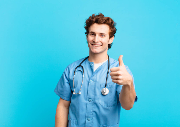 young nurse man feeling proud, carefree, confident and happy, smiling positively with thumbs up - Foto, imagen